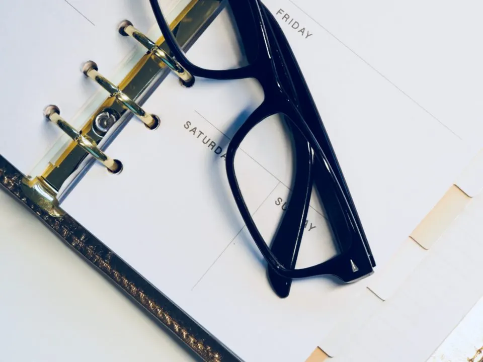 Óculos sobre uma agenda aberta nos dias de sexta, sábado e domingo